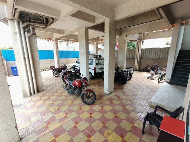 A van and motorcycles on the red and yellow checkered floor of the stilt parking — Rudra