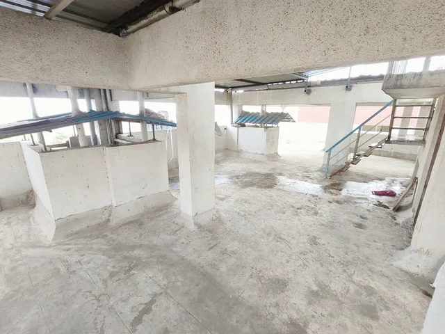 Blue metal canopies and a steel stair rail on the open rooftop, parapets on every side — Rudra, Karanjade